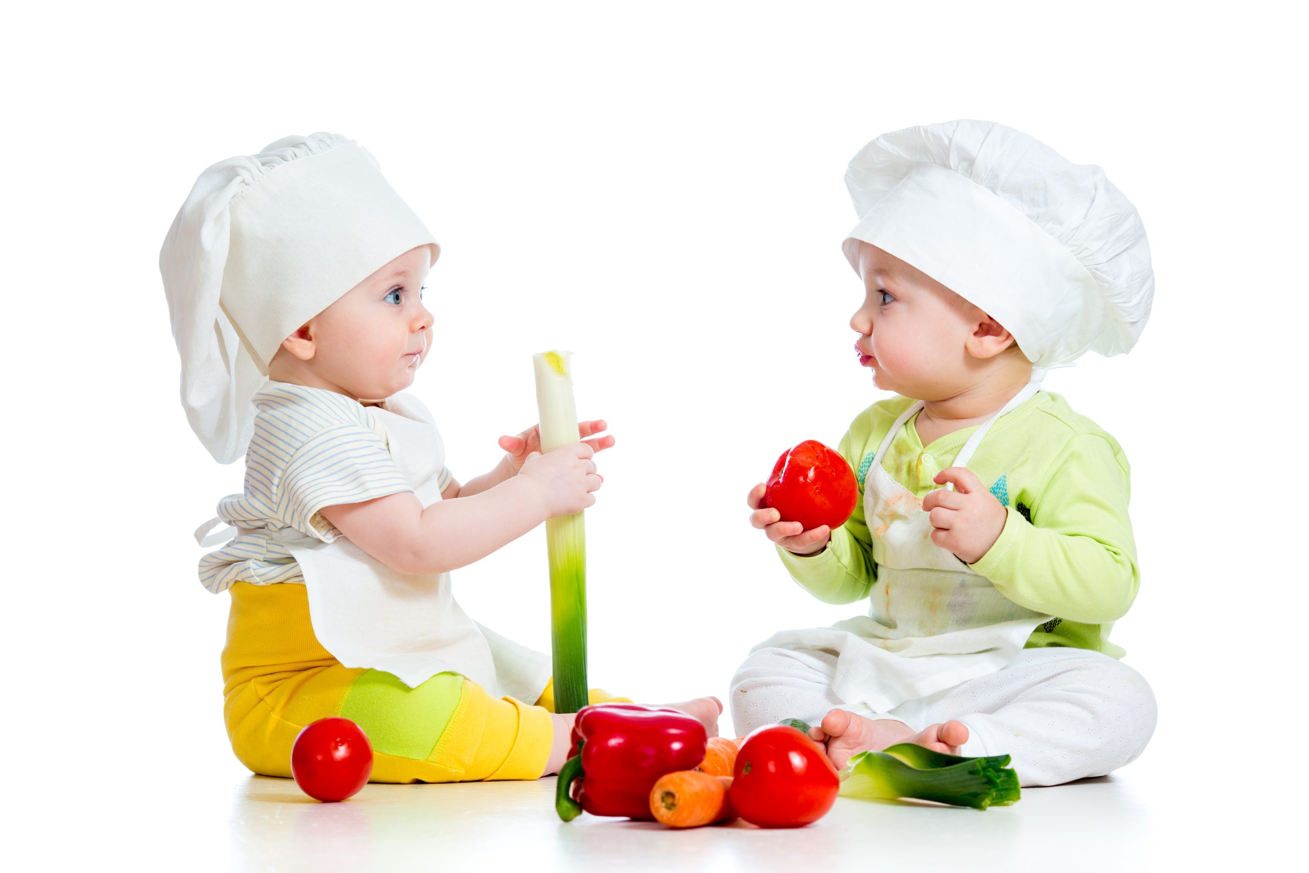 dve deti s kuchárskymi čiapkami na hlave jedia zdravú zeleninu