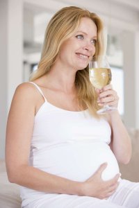 tehotná žena drží pohár vína a usmieva sa